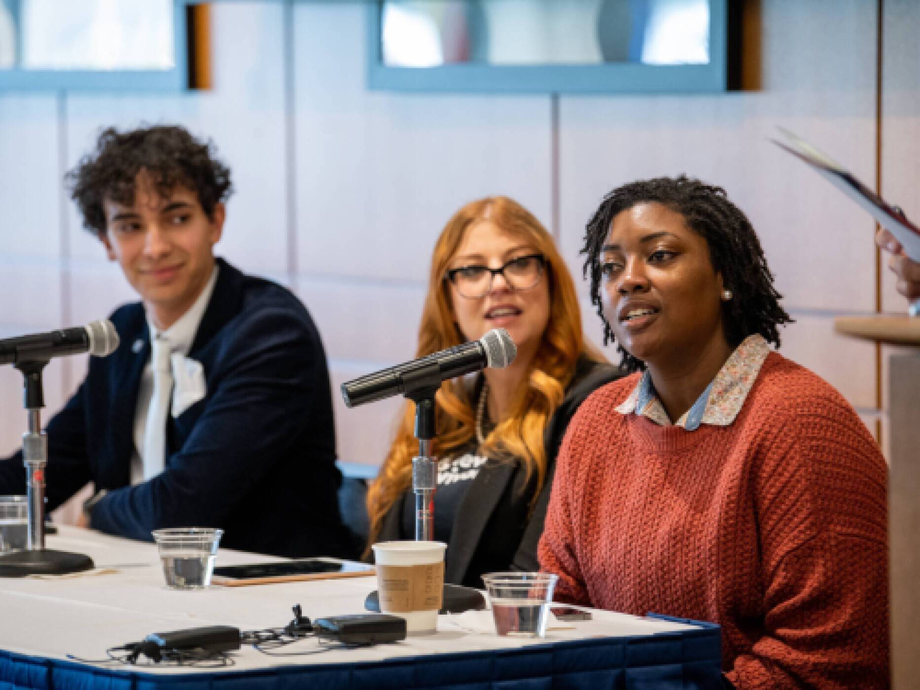 Three students sitting at a panel with microphones